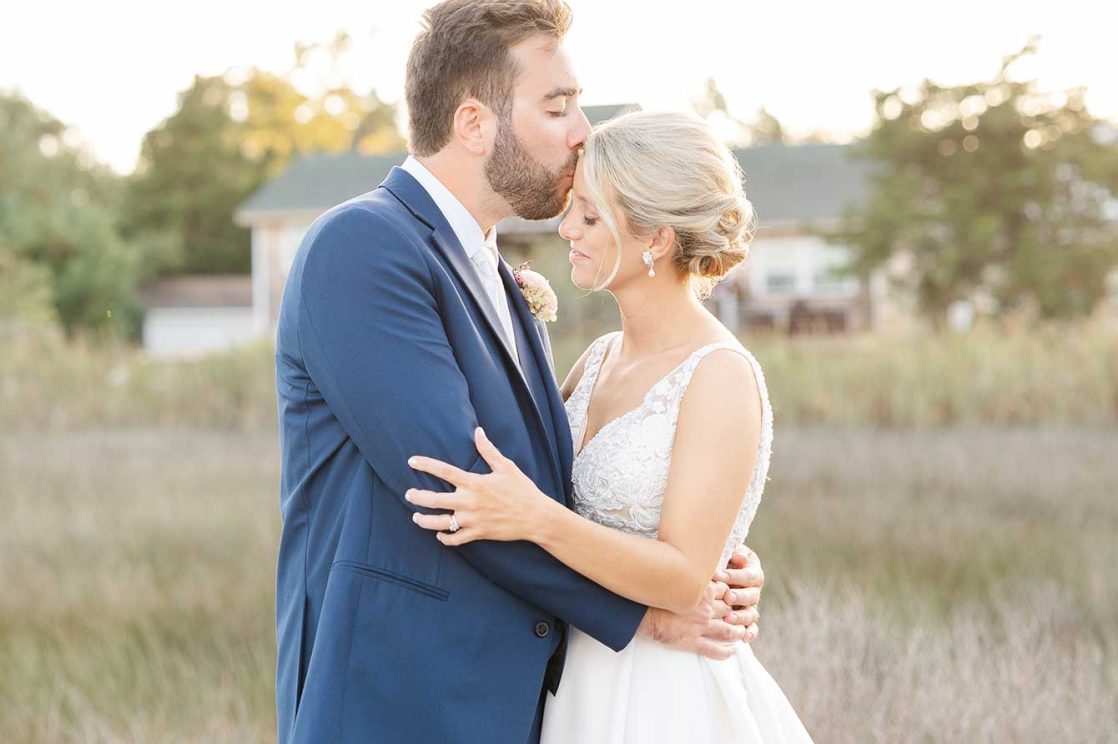 Groom kissing bride on forehead on the boardwalk